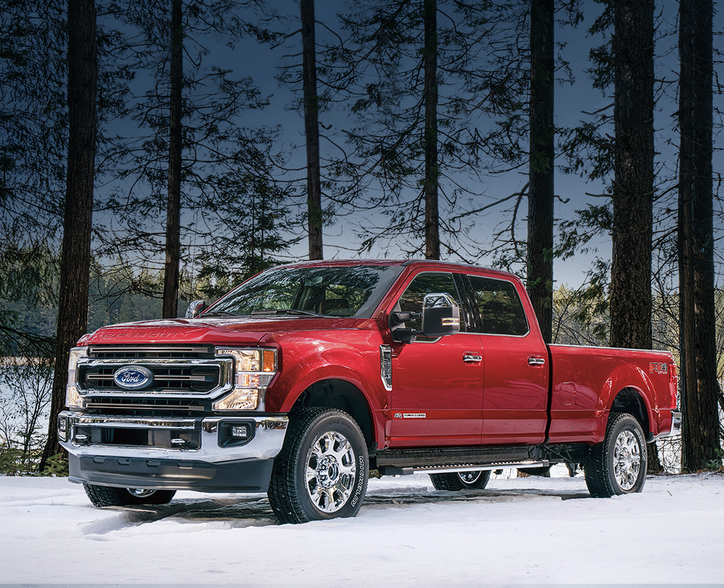 A Ford Super Duty is parked by a lake in a forest.