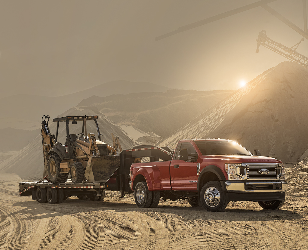 A Ford Super Duty continues to stay cool hauling construction equipment in a hot desert.