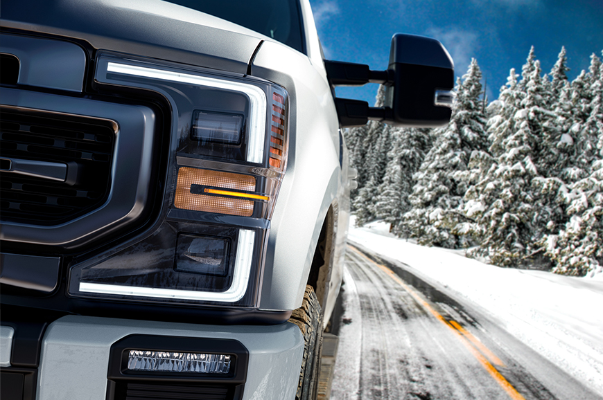 A Ford truck drives down a wintery highway.