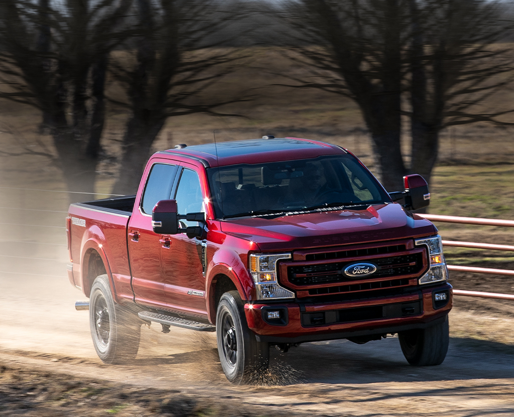 A Ford Super Duty drives down a country road.