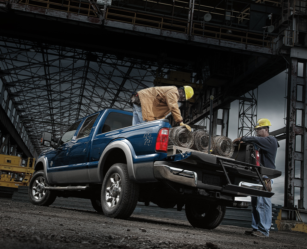 Two workers load fence coils onto a Ford truck.