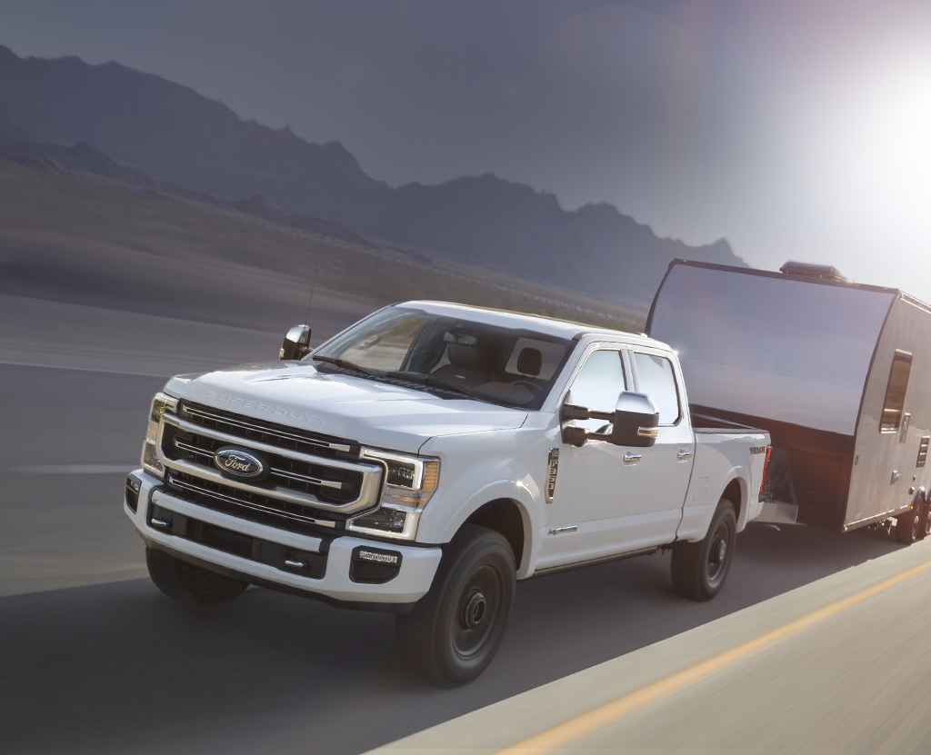 A Ford Super Duty hauls a trailer down the highway.