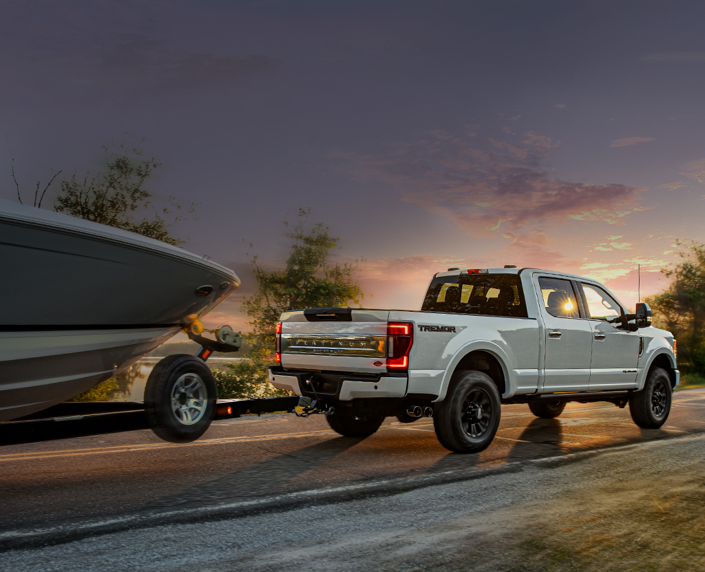 A Ford Super Duty hauls a boat at sunset.