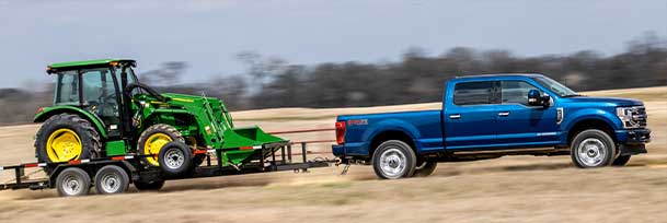 A Ford truck with a Power Stroke engine hauls farm equipment.