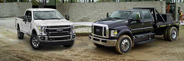 Two Ford trucks at a construction site.